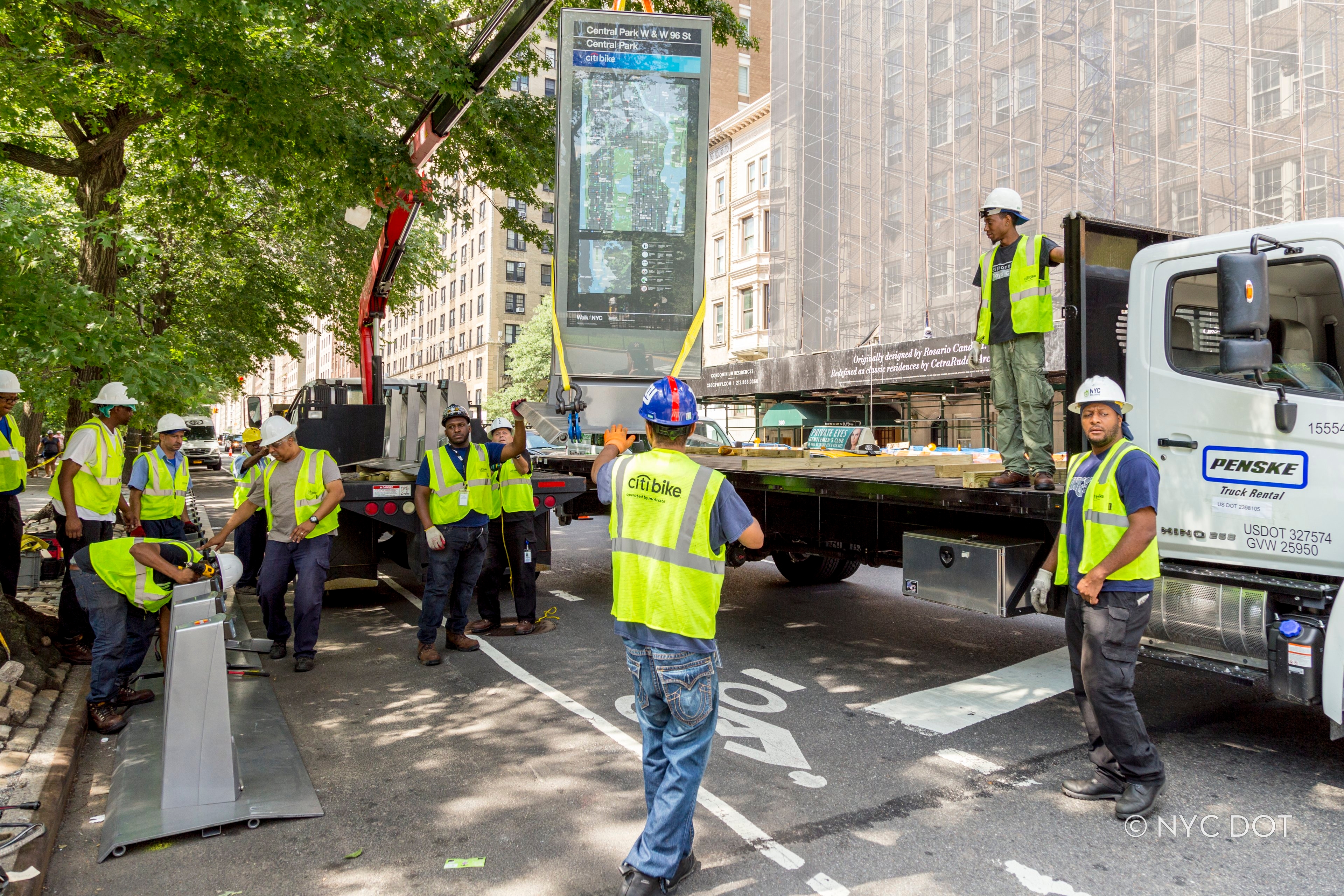 Citi Bike crew members install new Citi Bike station using crane.